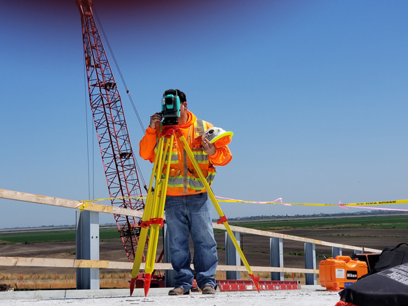 Surveyor at work at building site.