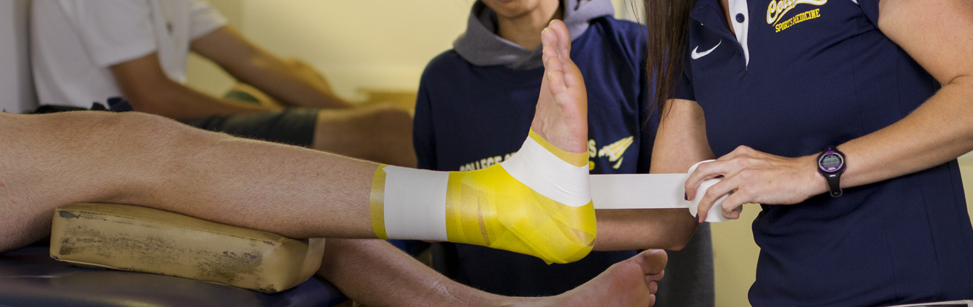 Sports Medicine faculty wrapping athlete's injuried ankle. 