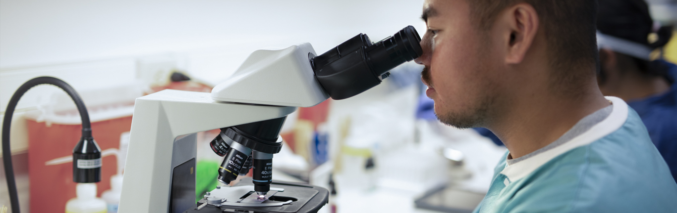 MLS Student looking through a microscope.