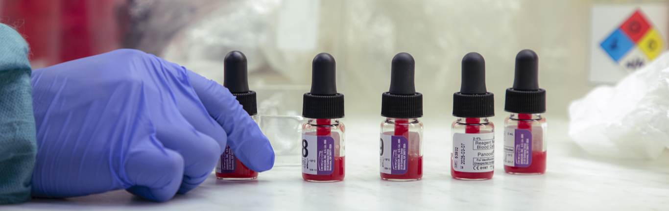 CLS student's glove handling blood vials in lab.