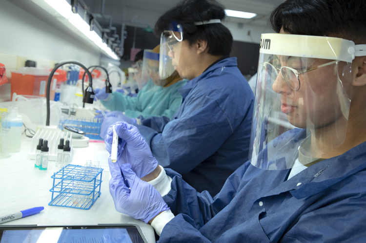 CLS students in lab coats and splash masks. 