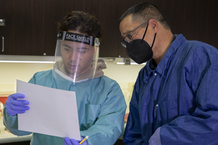 CLS instructor with student in lab coats and splash masks. 