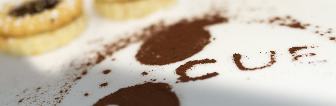iCUE logo made of dusted cocoa with 2 short bread cookies.