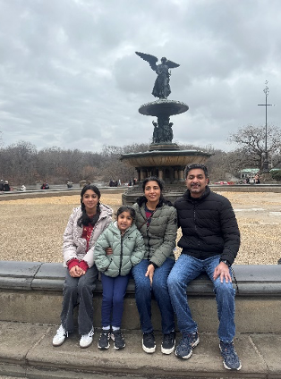 Image of a family of 4 people in front of a water fountain.
