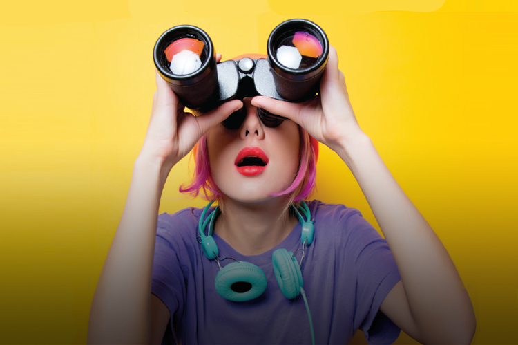 Female student gazing upward with binoculars.