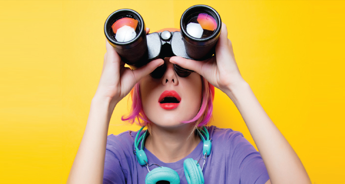 Discover Day: A young woman peers upward with binoculars.