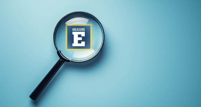 Composite illustration of Measure E under a magnifying glass.