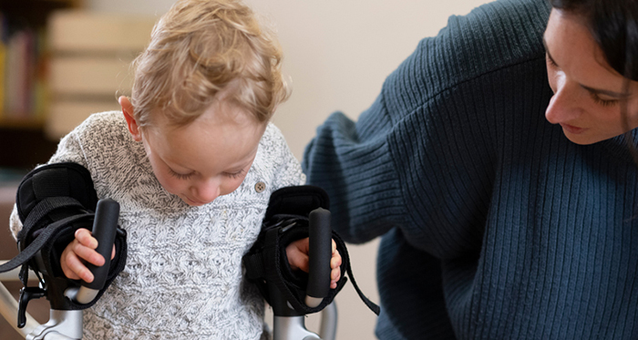 A physical therapist assistant helps a young girl's mobility.