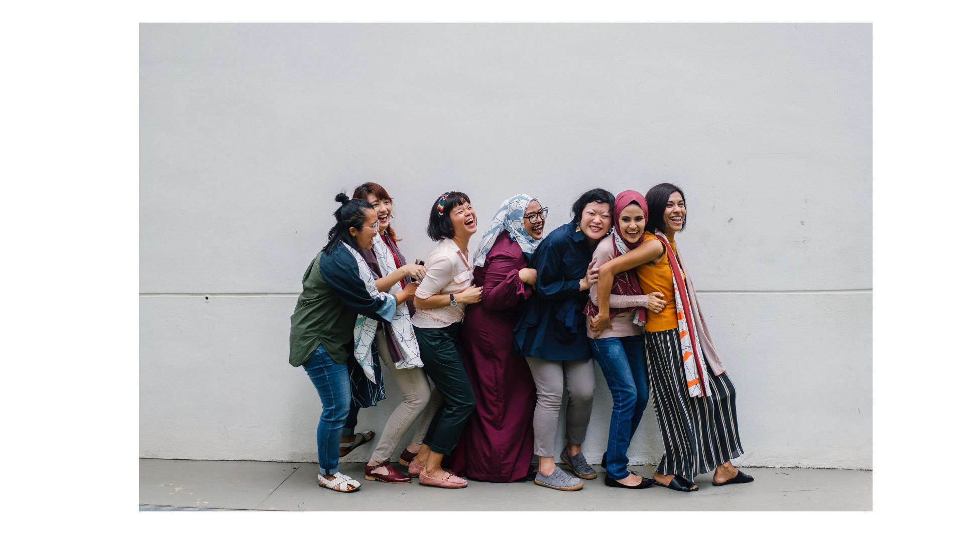 multi-ethnic and generational group of women standing together laughing
