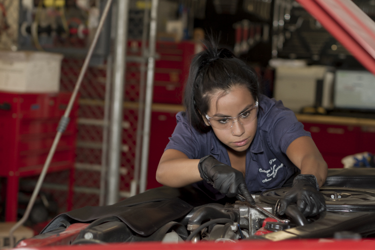 Automotive student working under the hood of a car. 