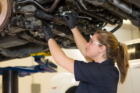 Auto mechanic student under the car on lift. 