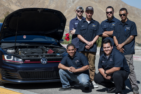 Auto mechanic students posing with their car hood up.  
