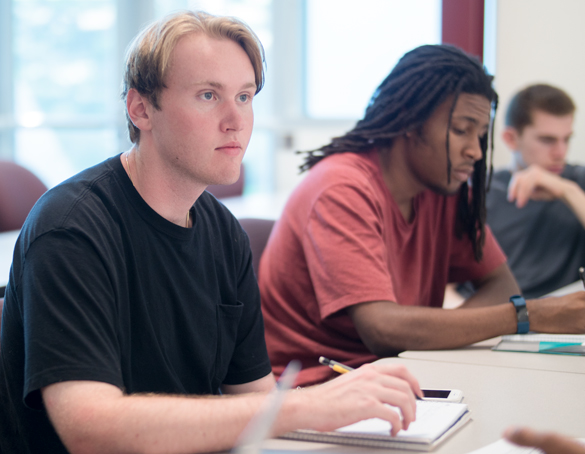 Buisness students in class working on projects, listening to instructor.  