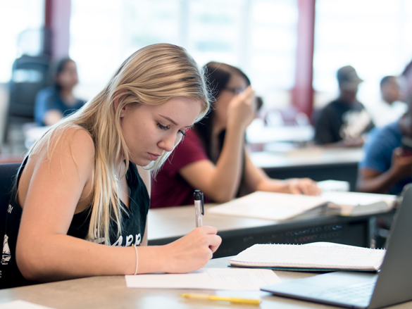 Buisness students in class working on projects, listening to instructor.  