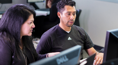 Student learning at computer with instructor. 