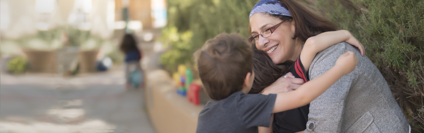 Children hugging their teacher at Early Childhood Education. 