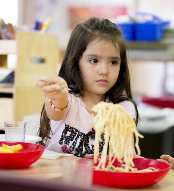 Child dishing out pasta at Center for Early Childhood Education. 