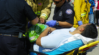 COC EMT student on ambulance stretcher with Fire and Ambulance personnel.