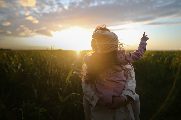 Daughter pointing at the sky in Mom's arms.