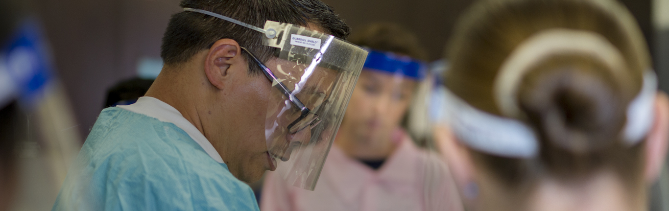 MLT instructor with students in lab coats and splash masks. 