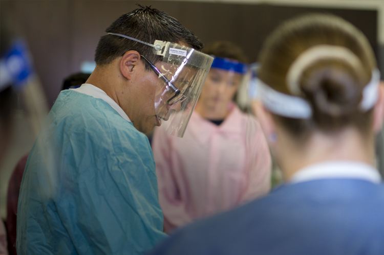 MLT instructor with students in lab coats and splash masks. 