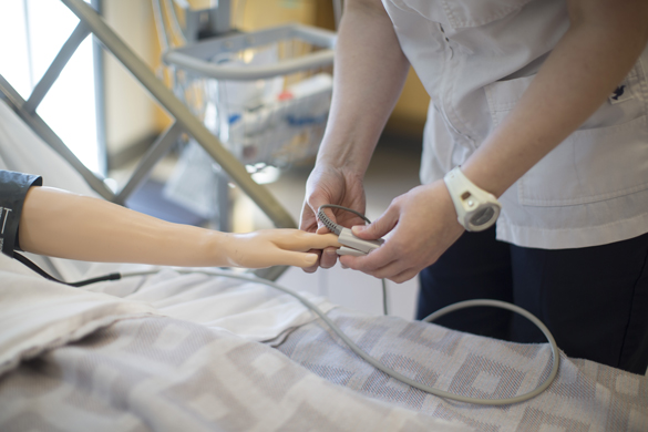 Nursing student checking finger pulse.