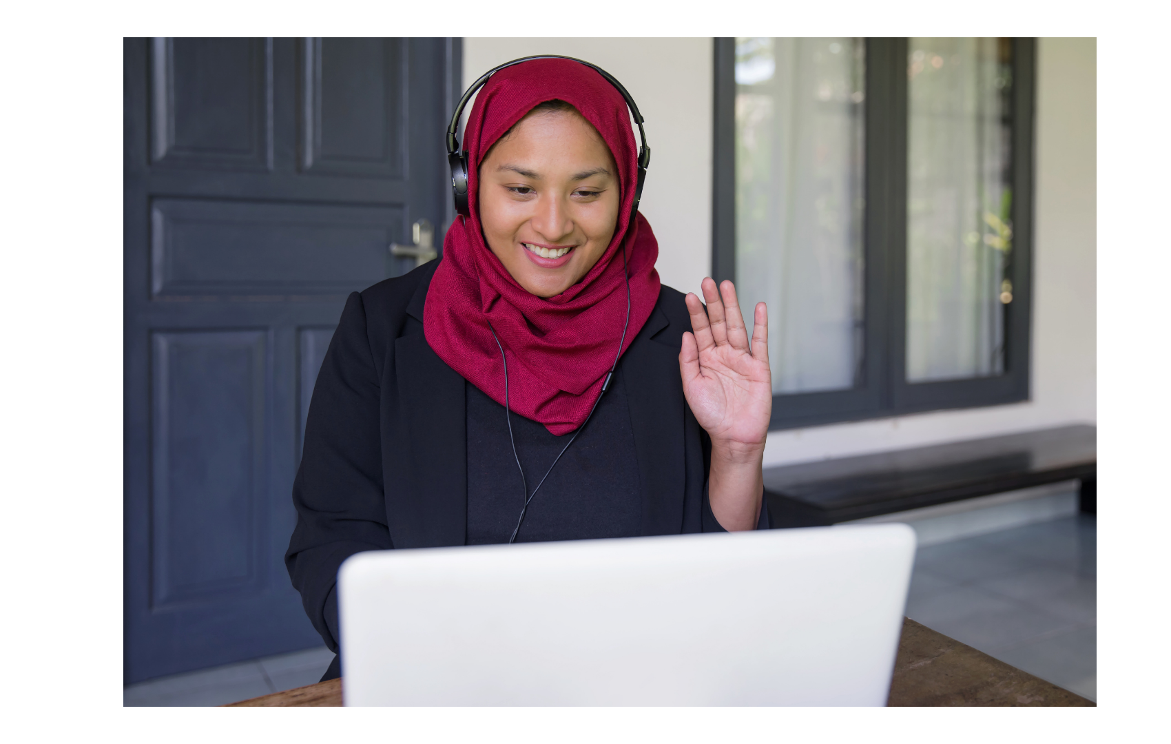 student waving hello to someone on a computer screen