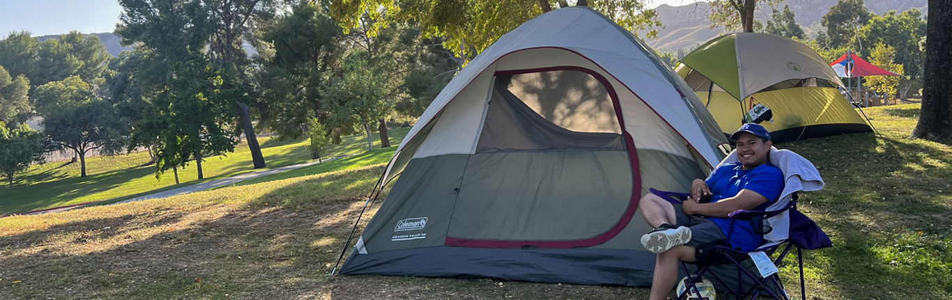 Student sitting next to his tent.