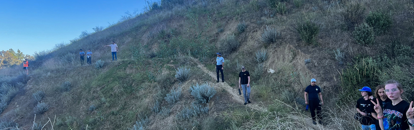 Students walking along a narrow dirt path on a hill.
