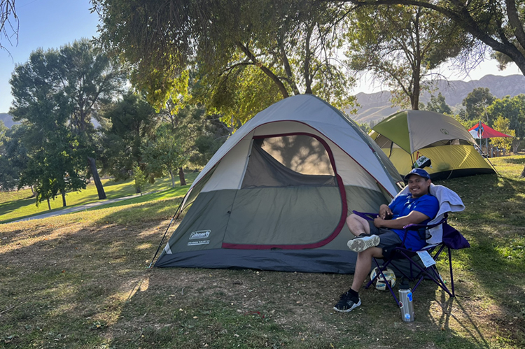 Student sitting next to his tent.