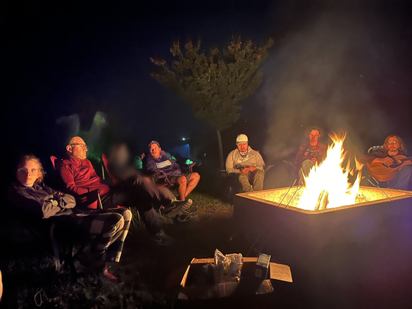 Students sitting around a nighttime campfire.