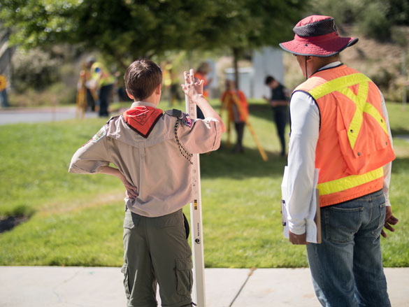 Boy Scout with surveying tool, with COC Surveying instructor assisting. 