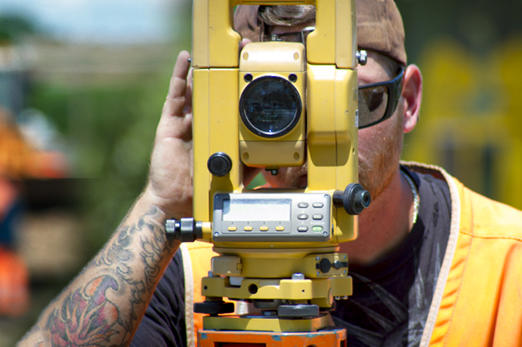 Surveying student looking through surveying equipment. 