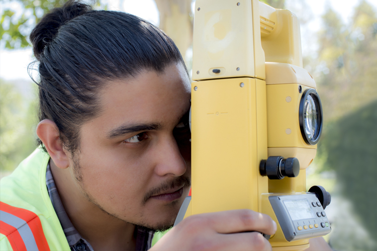 Surveyor looking through surveying equipment. 