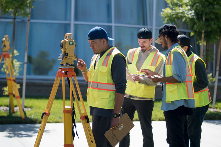 Surveying students looking through surveying equipment. 