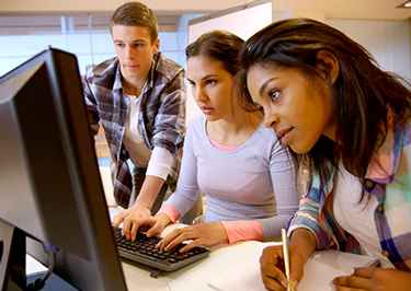 Students work together at a computer station.