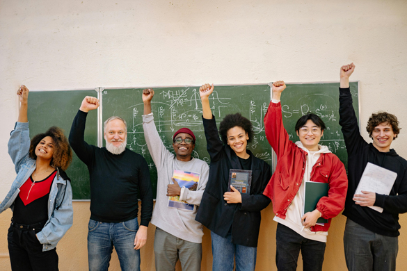 Ethnic variety of students with right hand raised for success.